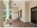 Inviting covered front porch with stone columns, brick pavers, bench, and dark wood front door at 508 Yellow Submarine Ct, Groveland, FL 34736