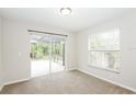 Bright bedroom with neutral carpet, slider to the screened in lanai and a bright sunny window at 111 Spring Ridge Dr, Debary, FL 32713