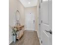 Inviting entryway with wood-look floors, stylish console table, a round mirror, and white doors at 12079 Scrub Palm Ln, Orlando, FL 32824