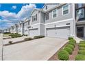 A row of neutral gray two-story townhomes, each with a private two-car garage and manicured landscaping at 12079 Scrub Palm Ln, Orlando, FL 32824