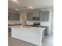 Modern kitchen with gray cabinets, quartz countertops, stainless steel appliances, and a central island at 1908 Diamond Head Cir, Lake Hamilton, FL 33851