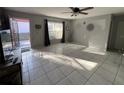 Well-lit living room with tile floors, ceiling fan, and view of the entrance at 68 S Marbrisa Way, Kissimmee, FL 34743