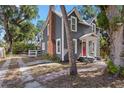 Two story home with gray siding, brick chimney, and mature trees at 821 E Lemon Ave, Eustis, FL 32726