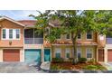 Inviting exterior of a two-story townhome with a private screened balcony, garage, and green front door at 12107 Poppy Field Ln # 105, Orlando, FL 32837