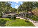 Aerial view of a well-maintained single-story home with a lush green lawn, mature trees, and a brick driveway at 2105 Fosgate Dr, Winter Park, FL 32789