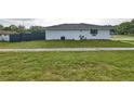 Exterior side yard of a white home, showcasing the neat lawn and a modern fence for added privacy at 211 Marion Oaks Ln, Ocala, FL 34473