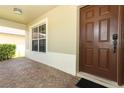 Covered entryway featuring a solid front door, keypad entry, and red brick style walkway at 212 Regency St, Davenport, FL 33896