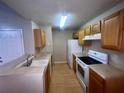 Kitchen features wooden cabinets, white appliances, laminate counters and wood-look floors at 2131 Cascades Blvd # 306, Kissimmee, FL 34741