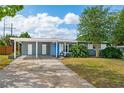 Street view of a charming home featuring a bright blue door, covered parking, and mature landscaping at 3520 Sebring Ave, Orlando, FL 32806