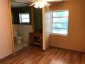 Bedroom with tan walls, desk, wood floors, window, and attached bathroom at 636 S Wellington Dr, Deltona, FL 32725