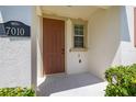 Welcoming front porch featuring a classic brown door, natural light from a window, and lush greenery at 7010 Broomshedge Trl, Winter Garden, FL 34787