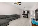 Spacious living room with tile flooring, an inviting gray couch, and an open layout to the kitchen at 7010 Broomshedge Trl, Winter Garden, FL 34787