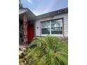 Quaint home featuring a red front door, stone details, and large windows at 7506 Mott Ave, Orlando, FL 32810