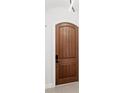 Elegant wooden front door with a modern black handle and lock, complemented by a white door frame at 8210 Topsail Pl, Winter Garden, FL 34787