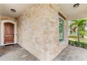 Charming front porch with stone accents, wooden door, tile flooring, and a view of the landscaped yard at 8210 Topsail Pl, Winter Garden, FL 34787