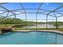 Screened-in pool with a waterfall feature overlooking a serene lake and lush greenery, perfect for relaxation at 850 Spring Oak Cir, Orlando, FL 32828
