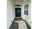 Inviting entrance to the home featuring a dark green front door, and welcome mat on a herringbone brick floor at 9959 Cypress Vine Dr, Orlando, FL 32827