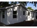 Rear view of the home showing white stucco exterior with multiple windows allowing natural light, and mature trees overhead at 1518 Indiana St, Orlando, FL 32805