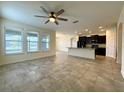 Bright living room featuring tile floors, ceiling fan, and natural light from the large windows at 274 Brunswick Dr, Davenport, FL 33837