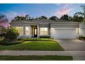 Attractive single-story home featuring a two-car garage, green lawn, and lush landscaping at dusk at 3456 Michigan St, Lake Mary, FL 32746