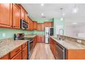 Well-equipped kitchen features wood cabinetry, granite countertops, and stainless steel appliances at 5839 Tarleton Way, Mount Dora, FL 32757