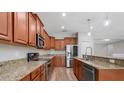 Spacious kitchen with stainless steel appliances, wood cabinets, granite countertops, and an island at 5839 Tarleton Way, Mount Dora, FL 32757