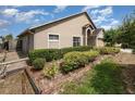 View of home's side and front showing manicured hedges and mulched garden bed at 6019 Long Peak Dr, Orlando, FL 32810