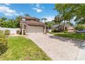 Charming two-story home featuring a brick driveway, a two-car garage, manicured lawn, and palm trees at 905 N Lake Claire Cir, Oviedo, FL 32765