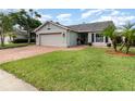 Well-manicured front yard featuring lush green grass, palm trees, and a brick paver driveway at 1096 Dees Dr, Oviedo, FL 32765