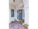 Inviting front porch featuring a blue door, brick floor, and decorative plants, creating a warm welcome at 11878 Via Lucerna Cir, Windermere, FL 34786