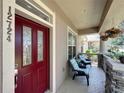Charming front porch featuring comfortable chairs, stone accents, and a stylish red door, creating a welcoming entrance at 12724 Bideford Ave, Windermere, FL 34786