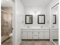 Bathroom with double sinks, framed mirrors, vanity lighting, and glass shower with tiled floors at 135 Heron Bay Cir, Lake Mary, FL 32746