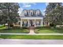 Charming yellow home showcasing a manicured lawn and white pillared porch beneath a dark roof at 1448 Conway Isle Cir, Belle Isle, FL 32809