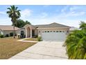 Inviting single-story home with a spacious driveway, two-car garage, and a lush palm tree in the front yard at 15 Sawfish Ln, Kissimmee, FL 34759