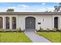 Close up of the arched front door with manicured landscaping and new exterior paint at 2327 Fieldingwood Rd, Maitland, FL 32751