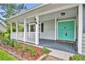 Inviting front porch with a teal door, white railings, and decorative landscaping at 2610 Cloudcroft Dr, Apopka, FL 32703