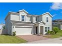 Attractive two-story home features a two-car garage and landscaped front yard under a clear blue sky at 683 Campo Ln, Davenport, FL 33837