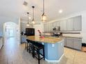 Open kitchen boasts a large island with pendant lighting, gray cabinets, and modern appliances for culinary enthusiasts at 1706 Leatherback Ln, St Cloud, FL 34771