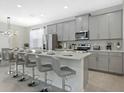 Contemporary kitchen boasts gray cabinets, stainless steel appliances, and an island with bar seating at 1929 Tropical Palms Cir, Kissimmee, FL 34747