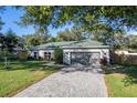 Charming single-story home with a gray exterior, a well-manicured lawn, and a paved driveway leading to a two-car garage at 2314 Pennsylvania Ave, Oviedo, FL 32765