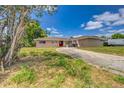 Front exterior showcasing a single-story home with a long driveway and well-manicured lawn at 409 Lake Ned Rd, Winter Haven, FL 33884