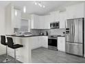 Stylish kitchen with white cabinetry, stainless appliances, and a breakfast bar at 833 Lockbreeze Dr, Davenport, FL 33897
