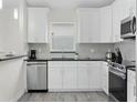 Modern kitchen featuring white cabinets, stainless steel appliances, and stylish backsplash at 833 Lockbreeze Dr, Davenport, FL 33897