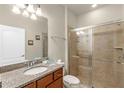 Bathroom with a granite vanity, wood cabinets, toilet, and a glass-enclosed shower at 8804 Rhodes Street, Kissimmee, FL 34747
