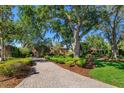 Beautiful brick home featuring mature trees, manicured shrubs and a brick driveway at 2828 Marquesas Ct, Windermere, FL 34786