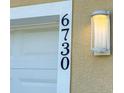 Close-up of the house number '6730' next to a modern outdoor light fixture at 6730 Orlando Drive, Indian Lake Estates, FL 33855