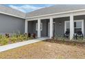 Inviting front entrance features a gray door, white pillars, and manicured landscaping at 72 Fairway Cir, Umatilla, FL 32784