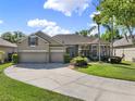 A tan home features a well-manicured lawn and a three-car garage at 14315 Letham Grange Ct, Orlando, FL 32828