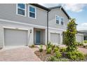 Two-story townhome featuring individual garages, manicured landscaping, and a pop of color at the front door at 16466 Bird Of Paradise Ave, Clermont, FL 34714