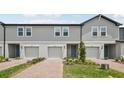 Gray two-story townhome featuring individual garages, neatly trimmed landscaping, and a blue front door at 16466 Bird Of Paradise Ave, Clermont, FL 34714